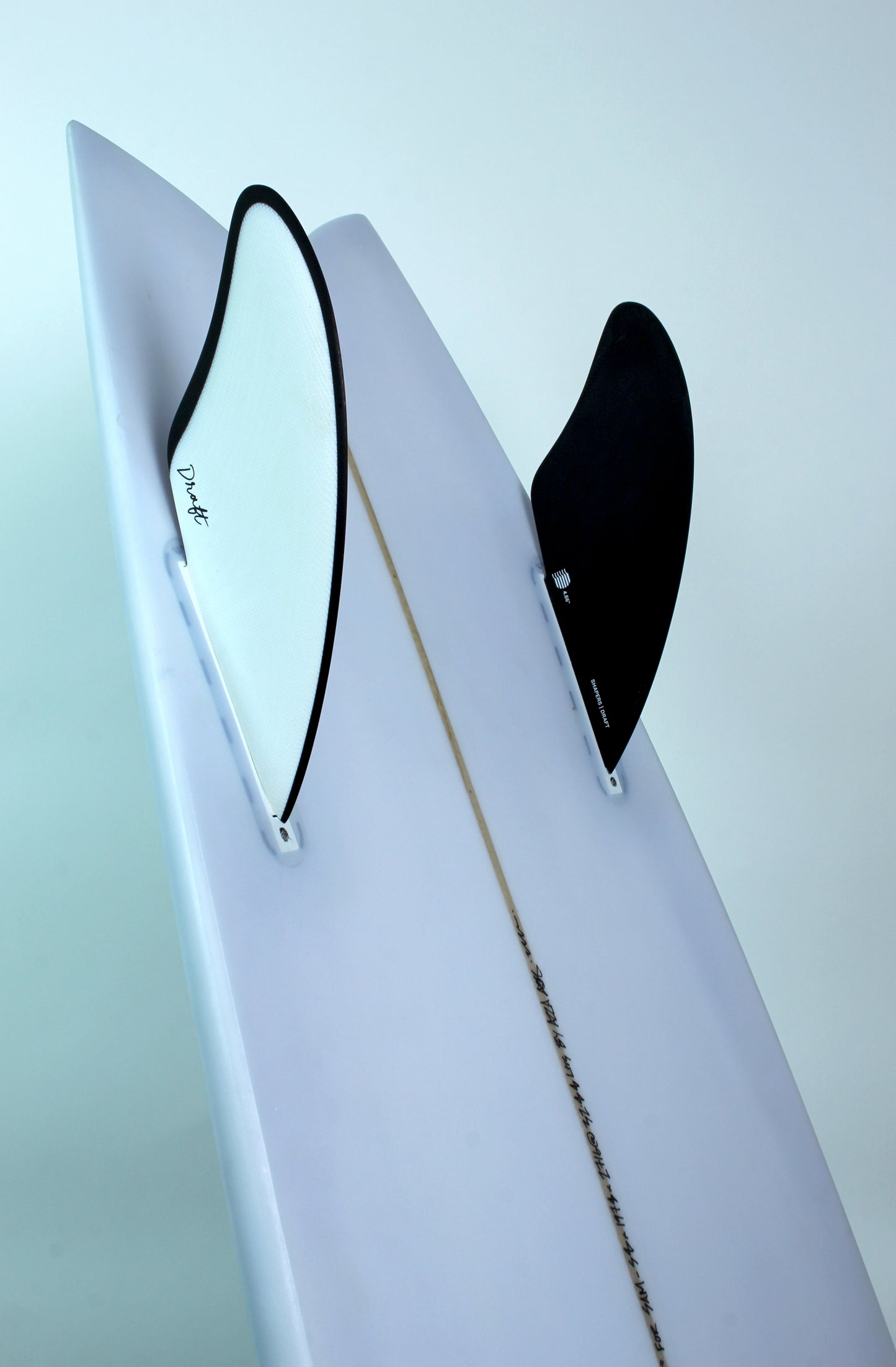 Draft Surf handcrafted surfboard with black and white twin fins, white deck, minimal style